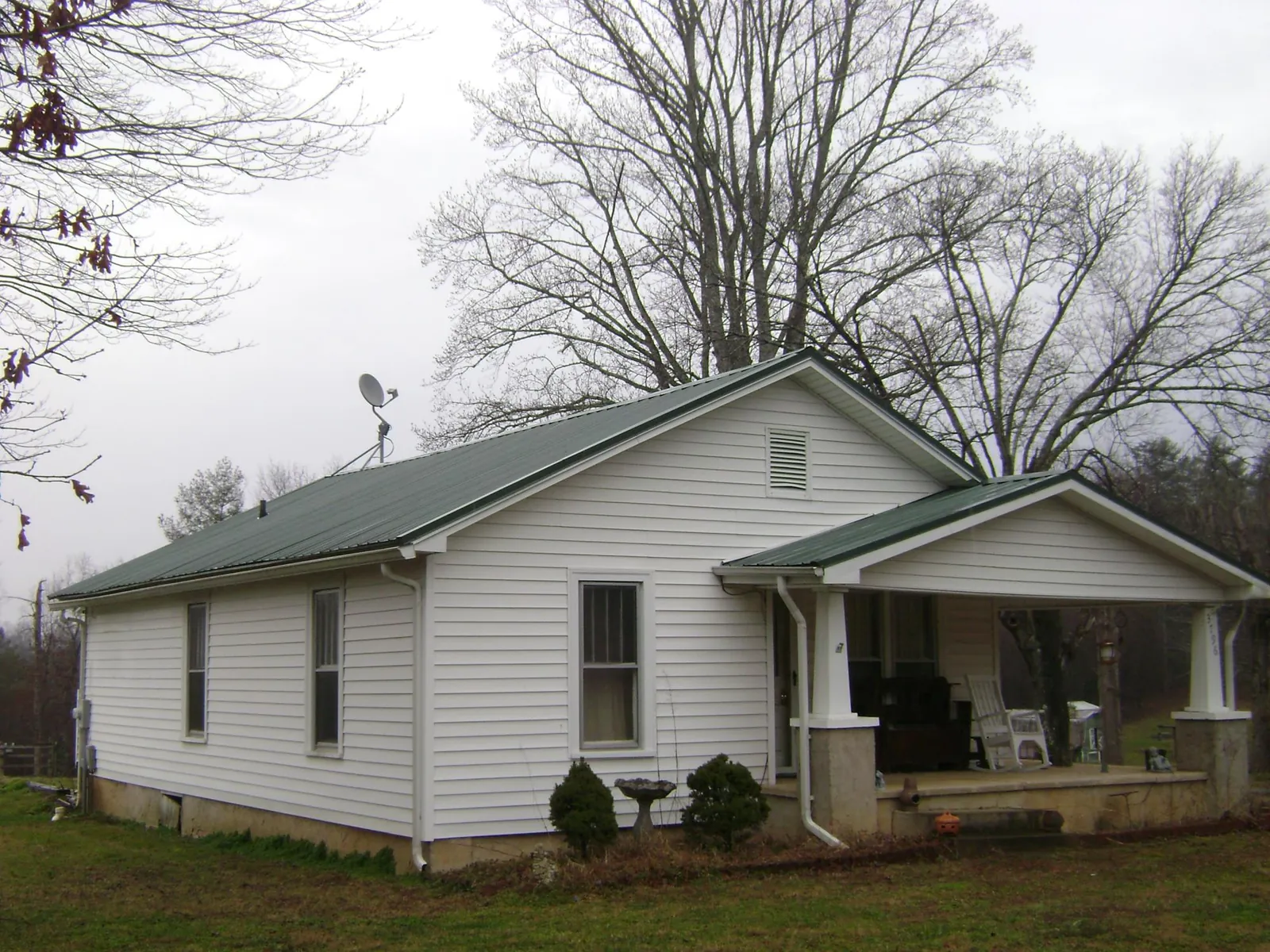 Green metal roof on a white bungalow with a side porch in Rockford