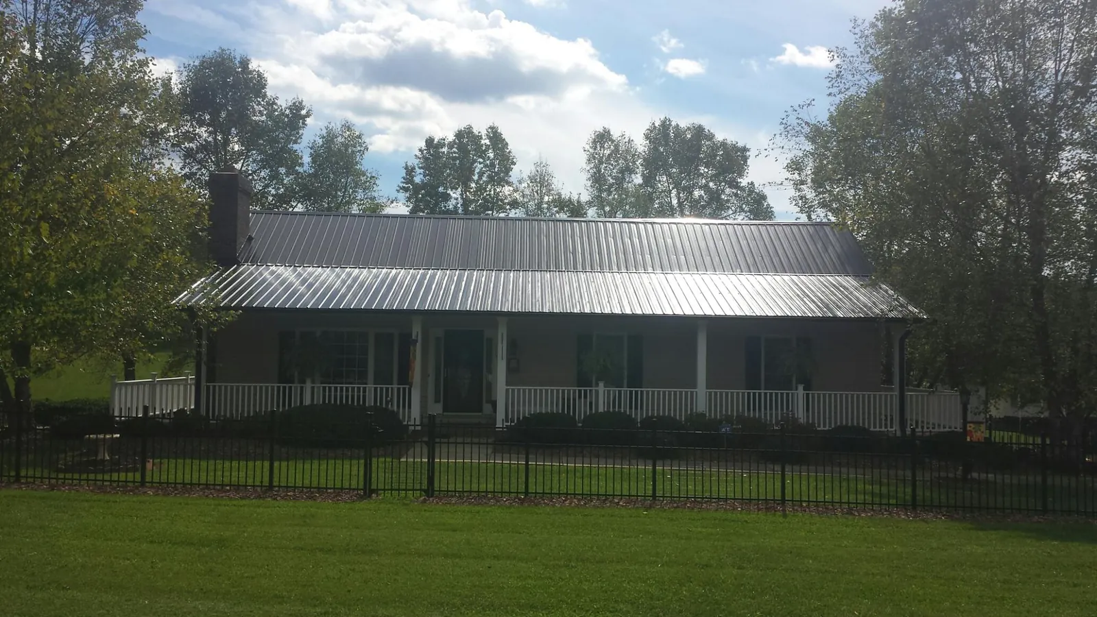Gray metal roof on a brick ranch with a full width front porch — Gutter Guard Installation work by our crew in Rockford